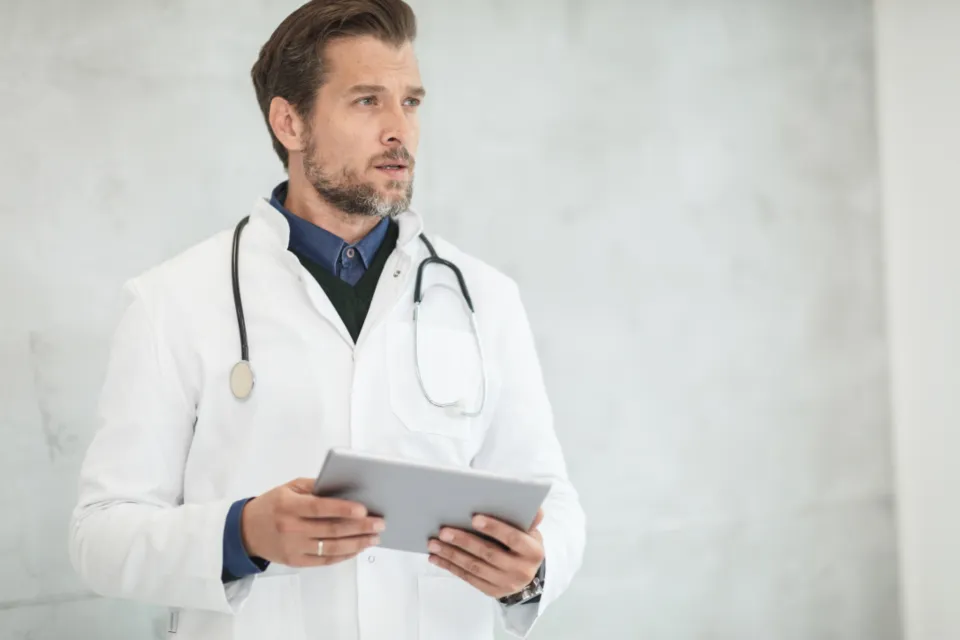 A doctor in a white coat reviewing a case on a tablet